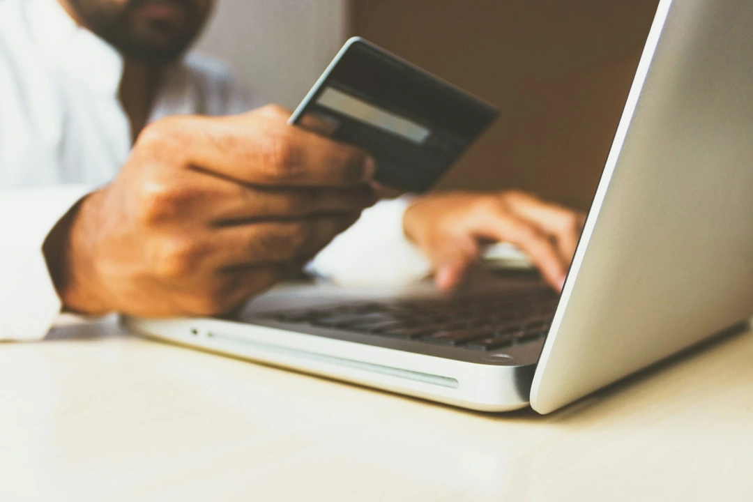 Hand using a laptop and a credit card, emphasizing digital van rental booking.