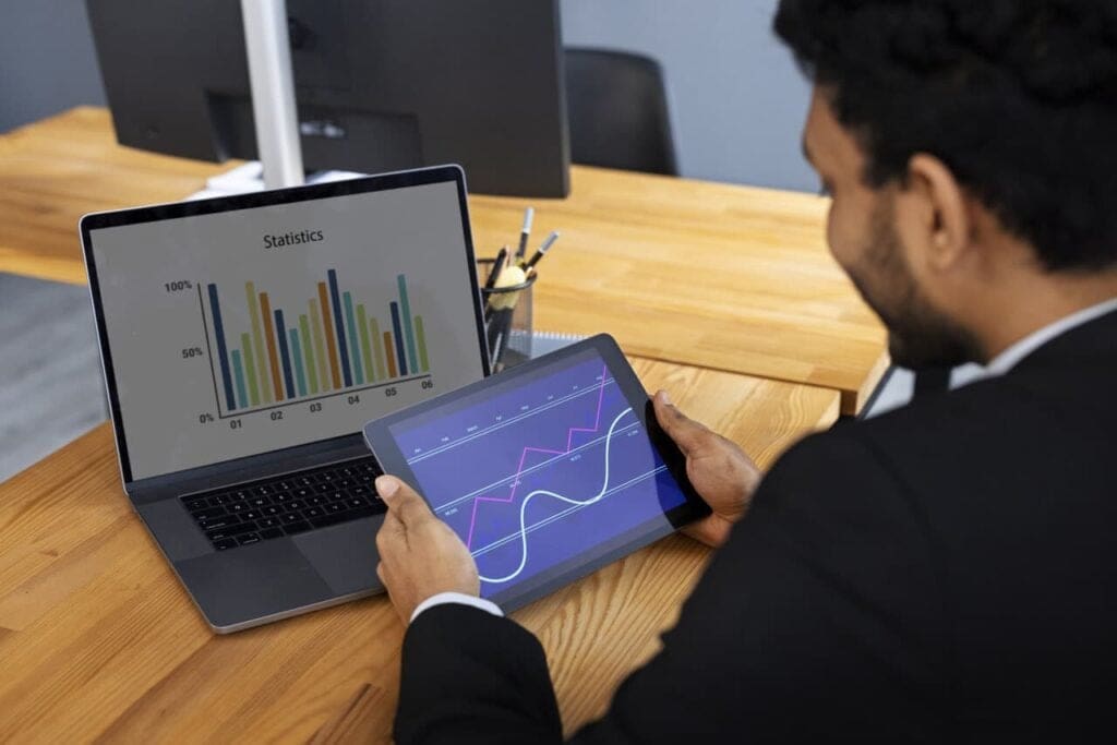 Person analyzing data on a laptop and tablet for better decision-making in equipment rentals